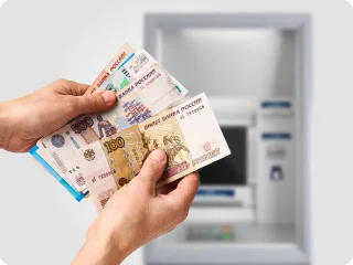 Деньги в руках на фоне банкомата